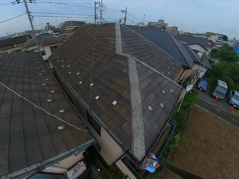 自撮り棒でカメラを伸ばして、屋根の状況や隣との距離を確認しています。